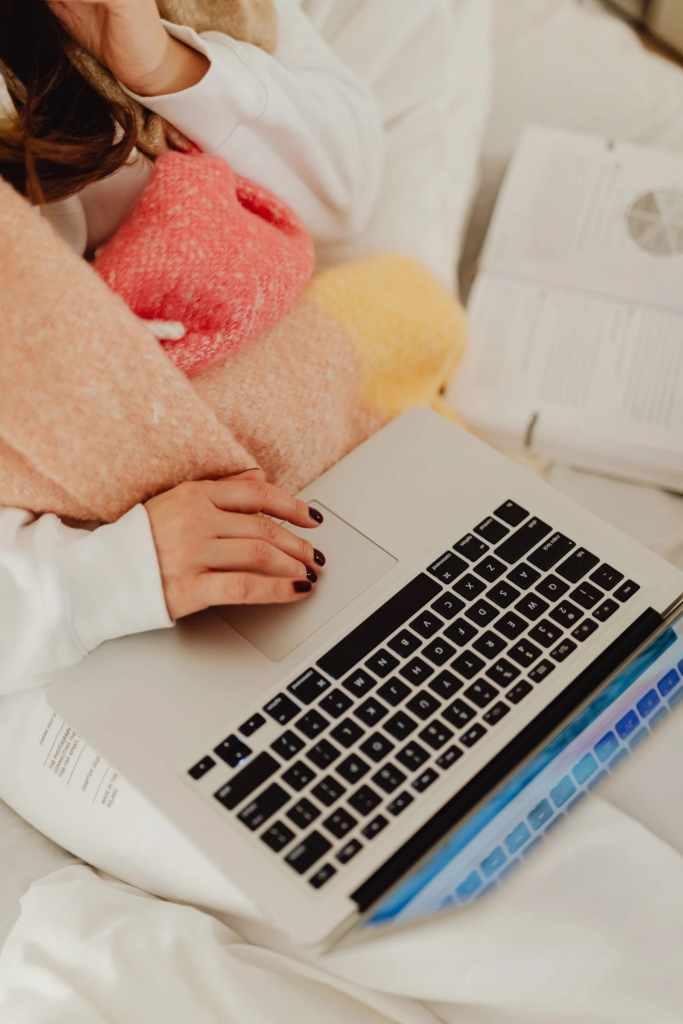 Person sitting on a bed with a laptop, signing up for the AssetWise Institute email list.